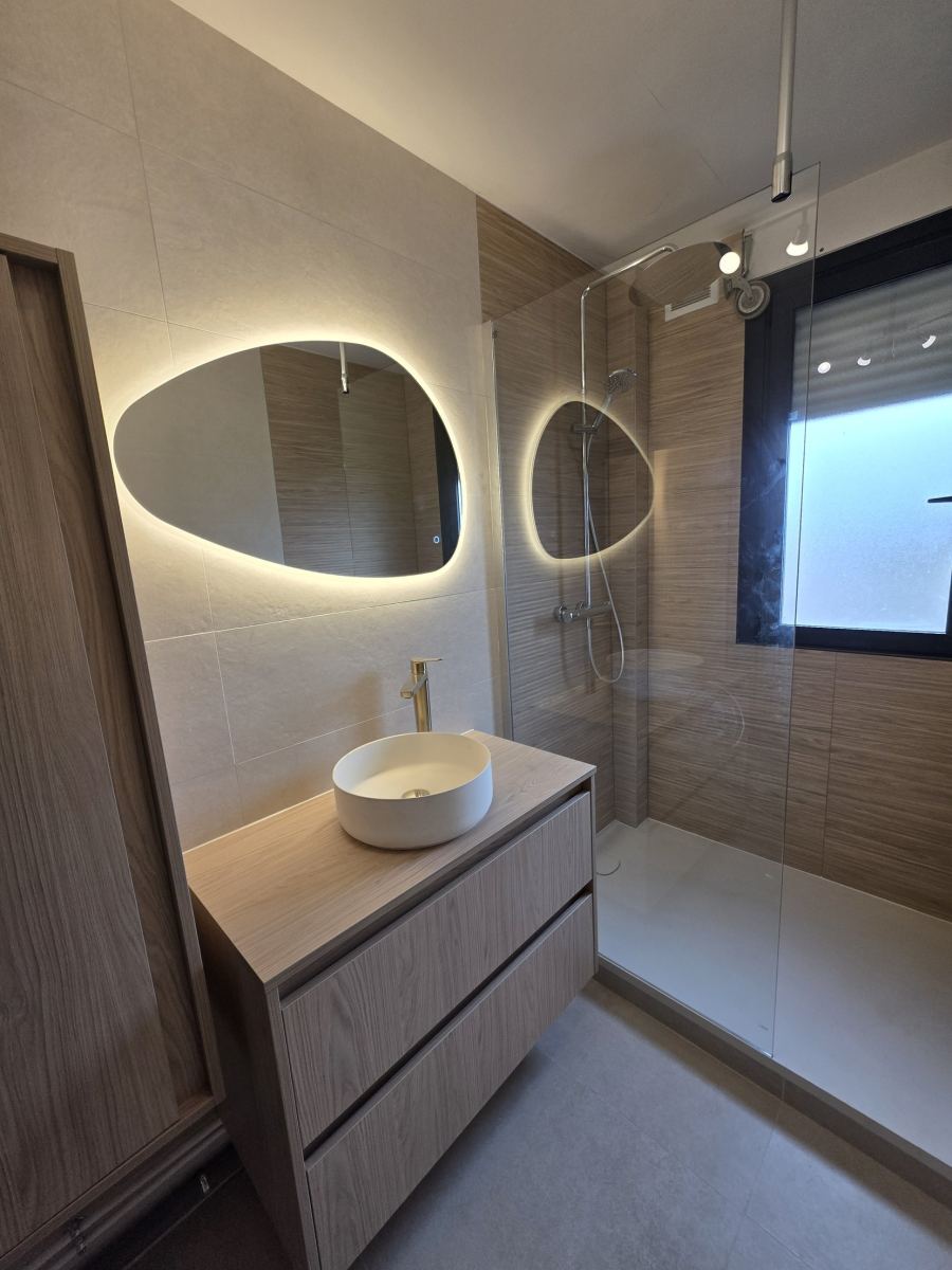Salle de bain avec meuble bois, vasque à poser, miroirs rétroéclairés et douche avec receveur extra-plat