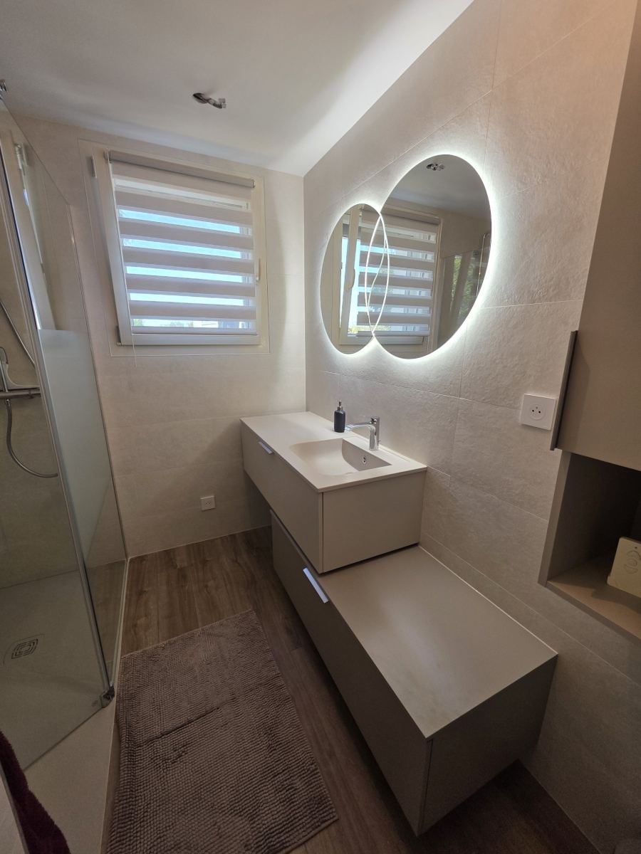 Salle de bain avec plan vasque, miroirs ronds rétroéclairés et douche